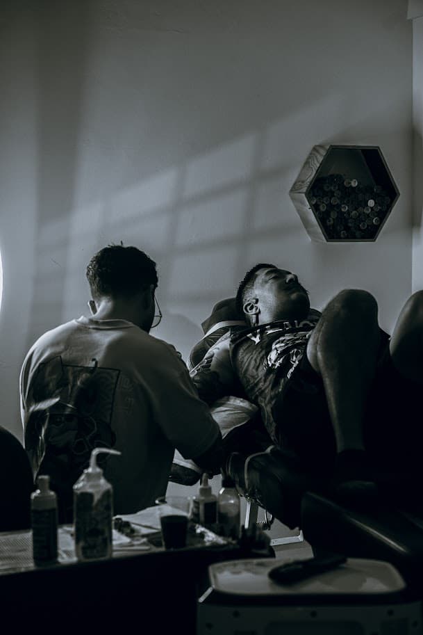 Interior de estudio de tatuaje boutique en Medellín con muebles de roble oscuro, sillas vintage de cuero y detalles dorados bajo iluminación dramática