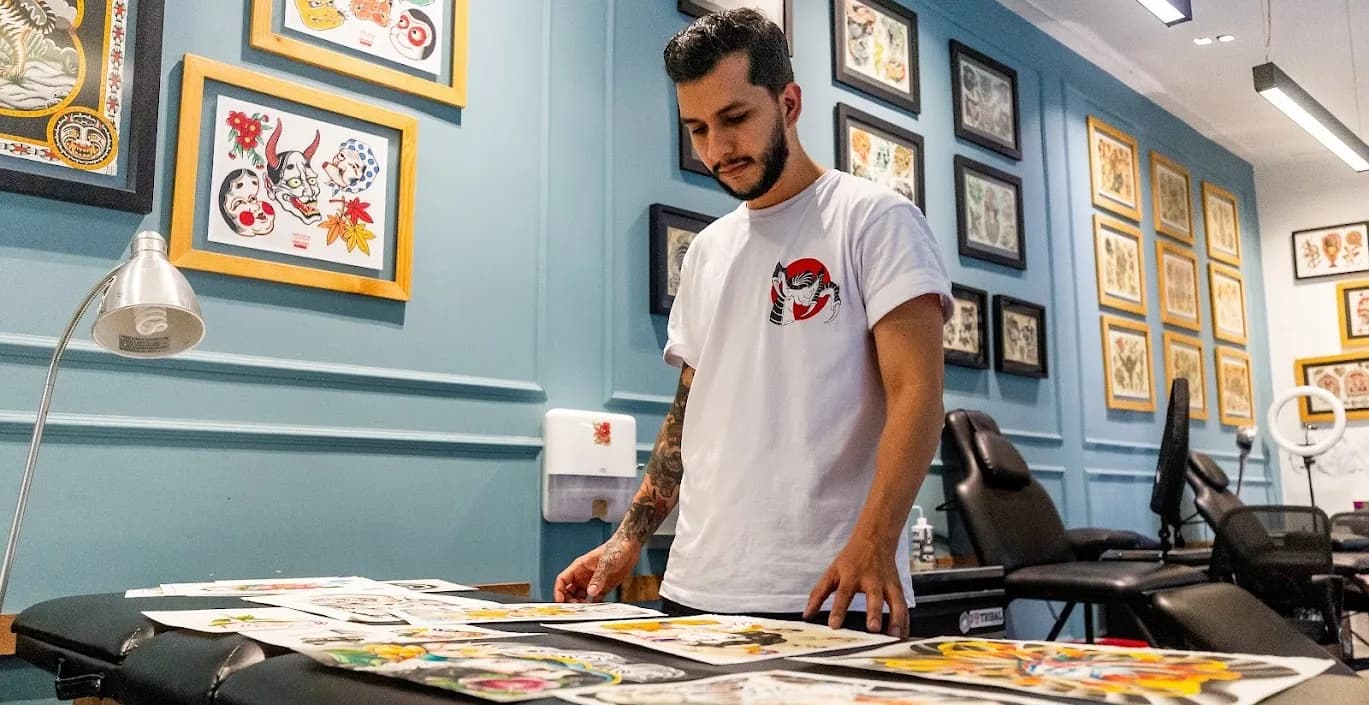 Interior de estudio de tatuaje boutique en Medellín con muebles de roble oscuro, sillas vintage de cuero y detalles dorados bajo iluminación dramática